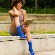 Woman reading & wearing blue herringbone compression crew socks