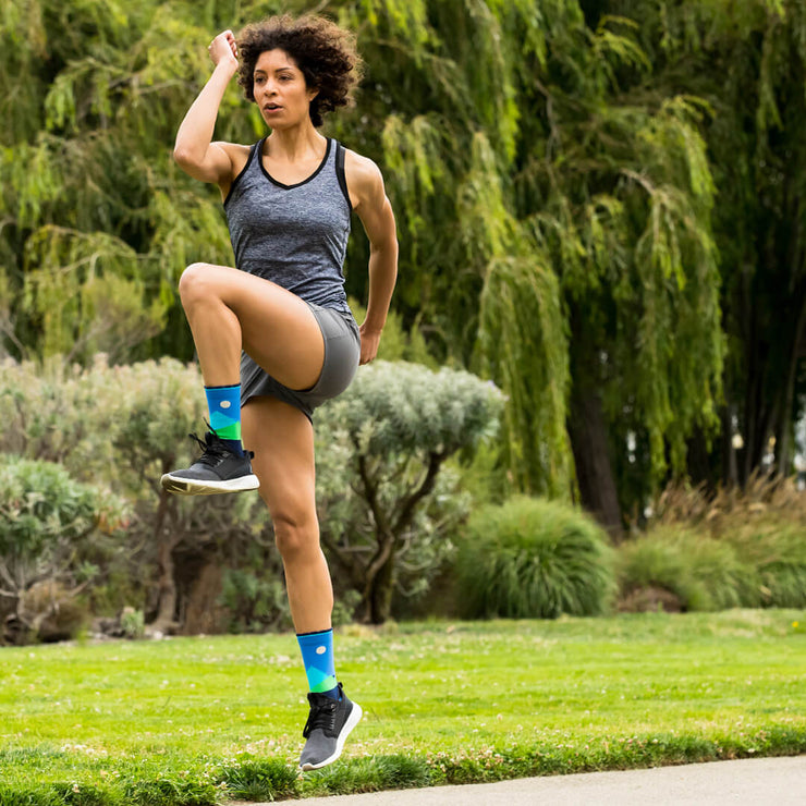Woman exercising outdoors in blue compression crew socks with moonlit mountains design