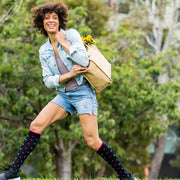 Woman with shopping bag wearing black compression socks with pink and light blue dots