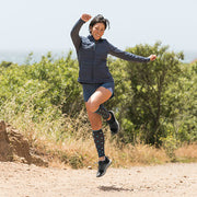 Runner doing a skip wearing slate polka-dotted compression calf sleeves