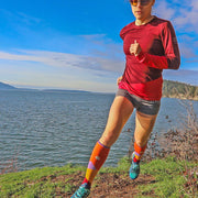 Designer performance compression socks with mountains on a moonlit sky in orange on trail runner 